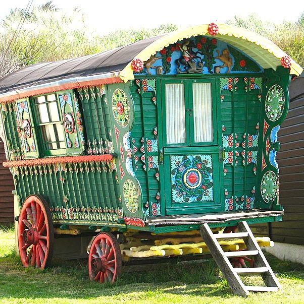 A green wagon with a door and windows painted in folk art style.