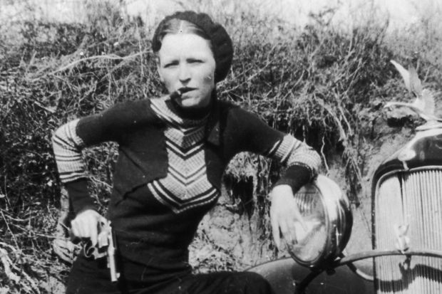 A woman sitting on top of a bike in the grass.