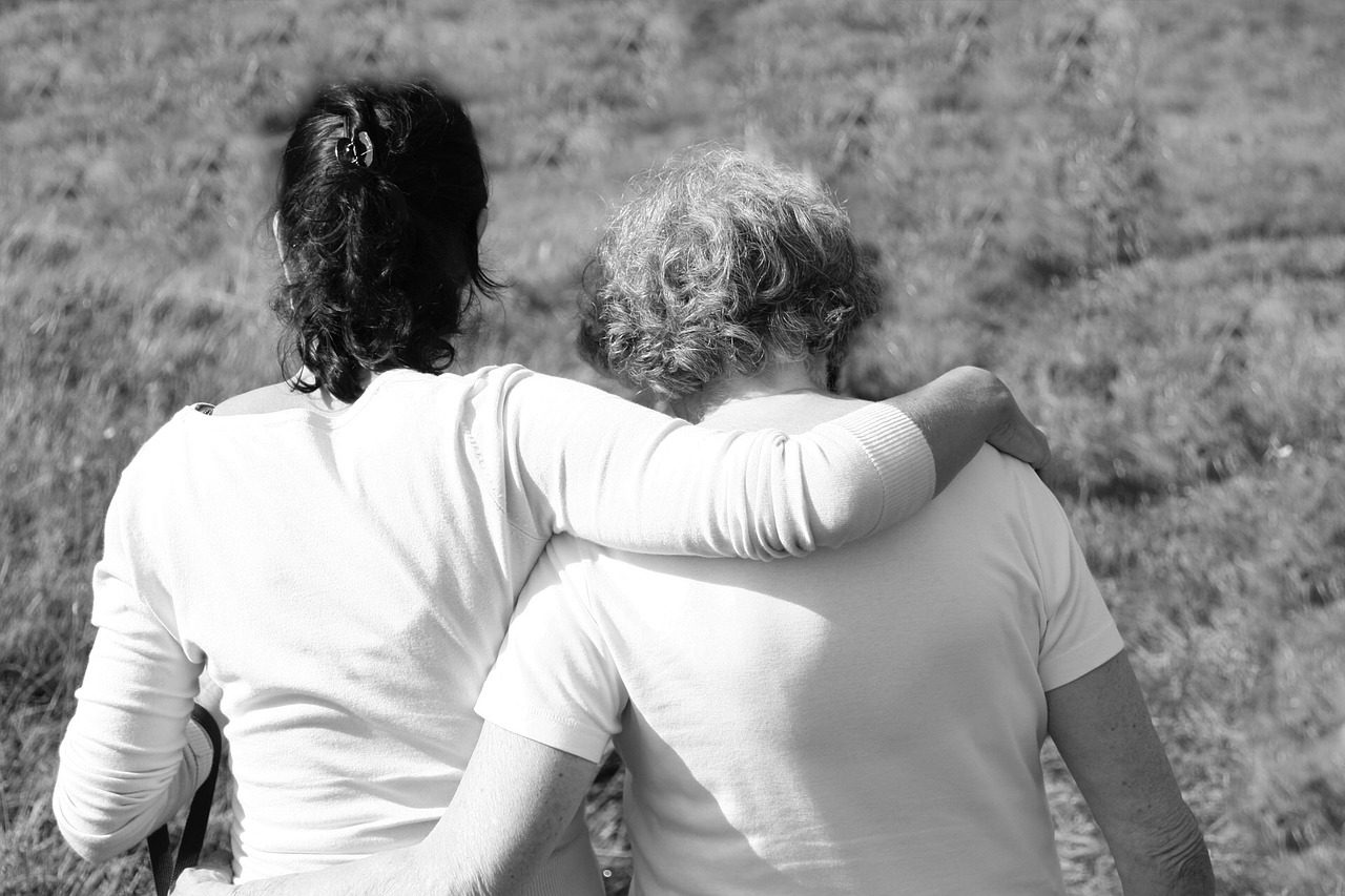 Two women are hugging each other in a field.