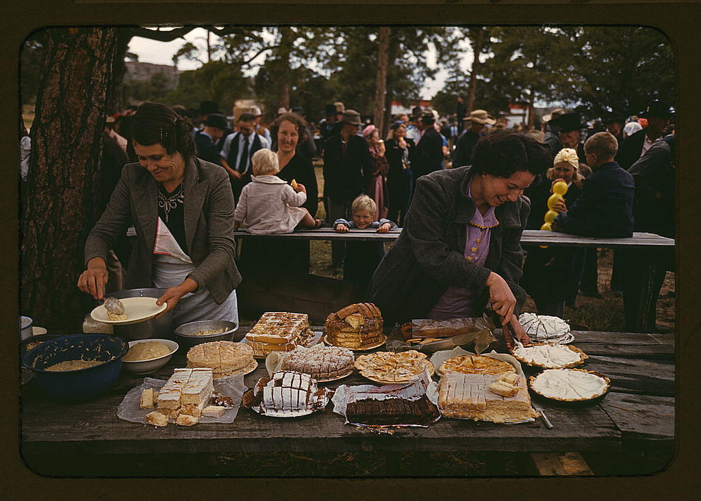 A group of people standing around a table with food.