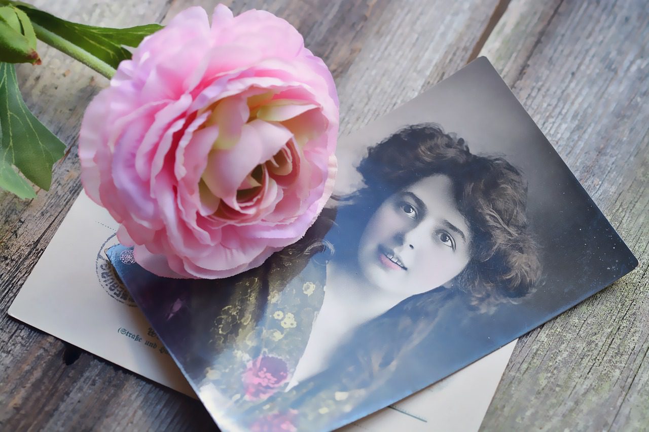 A pink rose and an old photograph on top of papers.